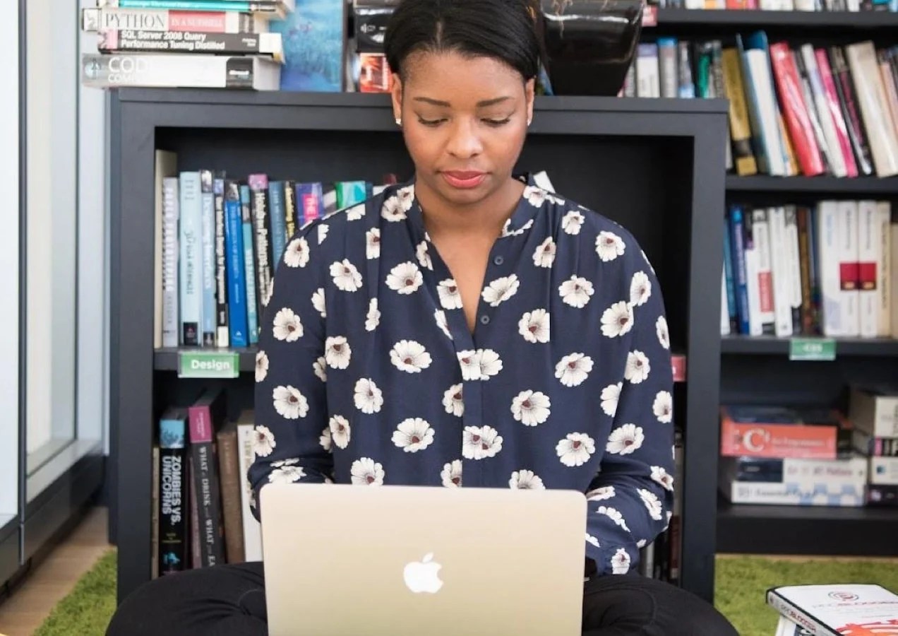 woman working in an office on a computer with books in the background