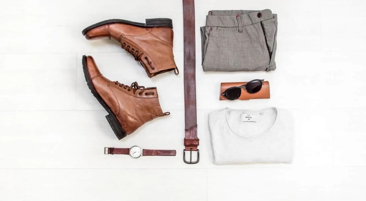 flatlay of men's clothing, including boots, pants, and accessories