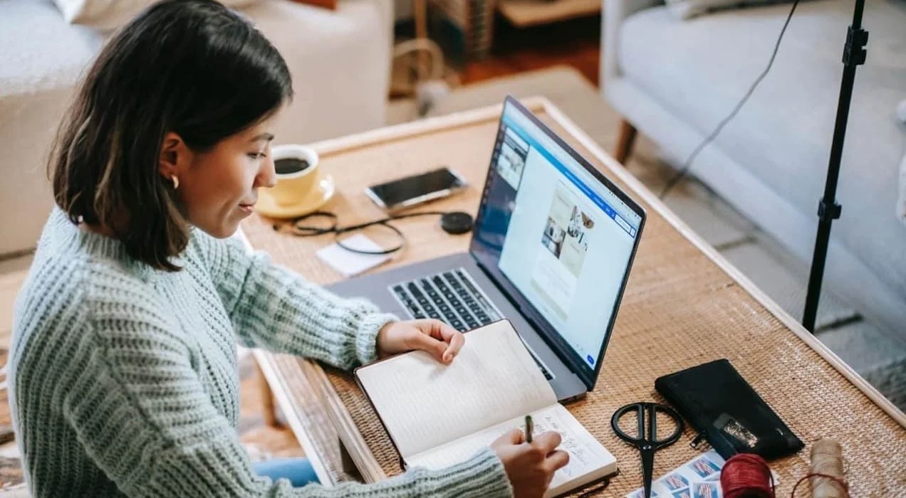 woman working at a desk with a notebook and laptop