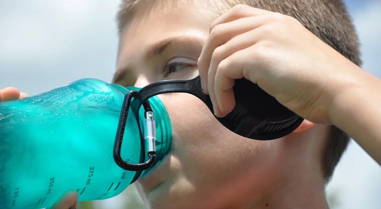 boy drinking out of a blue water bottle
